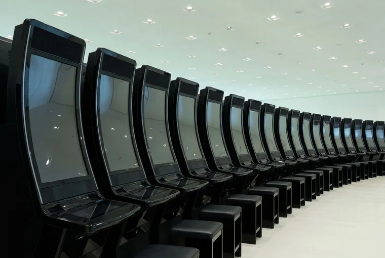 Une longue rangée courbe de grands écrans de jeu noirs, éteints, dans une salle claire.